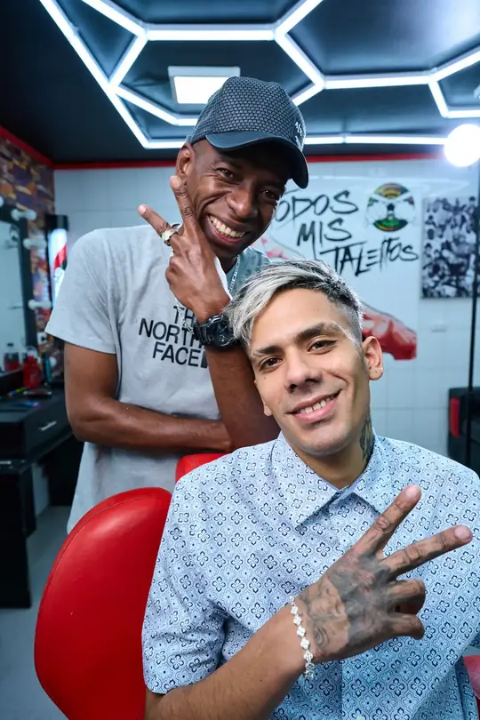 Dos barberos de El Ñaño junto al sillón rojo