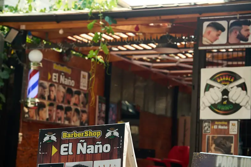 Entrada de Barbería El Ñaño con su poste de barbero